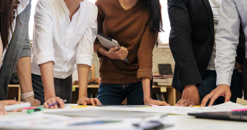 Group of people working on paperwork spread on a table