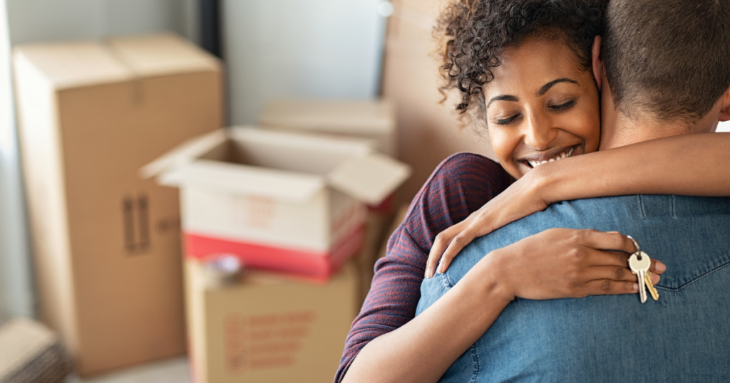 couple hugging with keys in hand and boxes in background