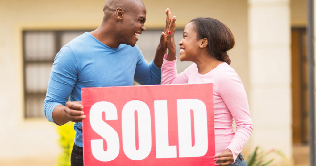 couple high fiving with a sold sign